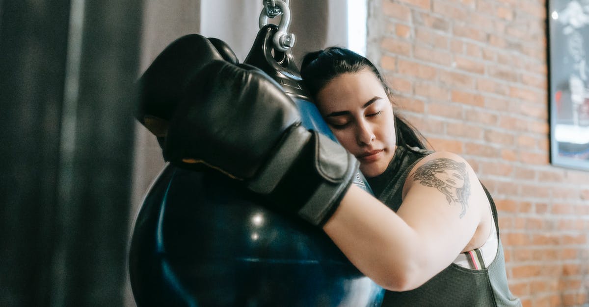 Pressure canner physics - Exhausted female with closed eyes lying on punching ball while having break in boxing workout in gym