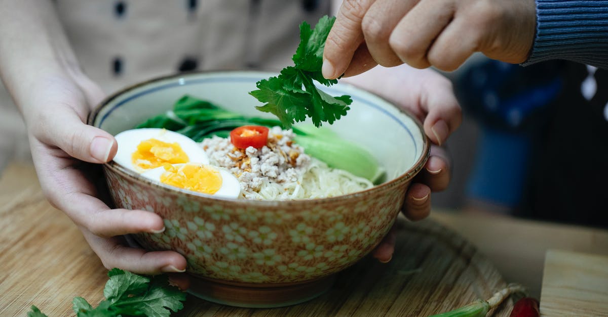 pressure cooker overflowing while cooking soup - Crop unrecognizable women decorating Asian noodle soup with parsley