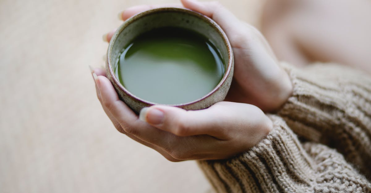 Preventing matcha deposits - High angle of crop anonymous female in knitwear with ceramic cup of hot matcha tea