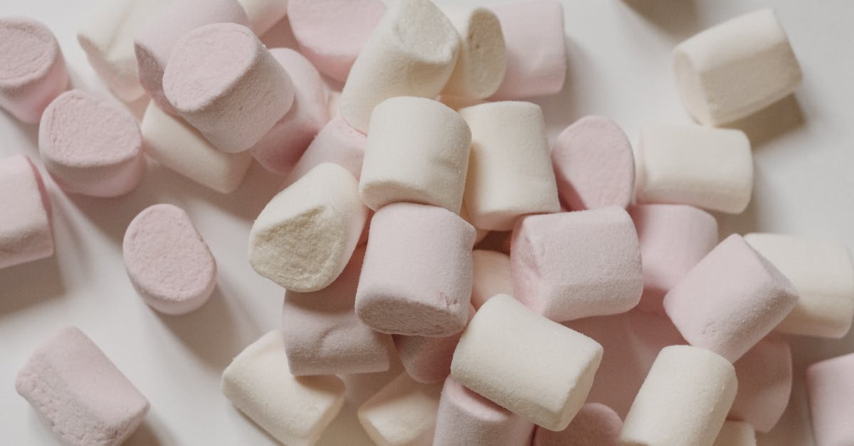 Preventing white sugar from clumping in the canister - Top view arrangement of sweet delicious marshmallows of light color heaped on white surface