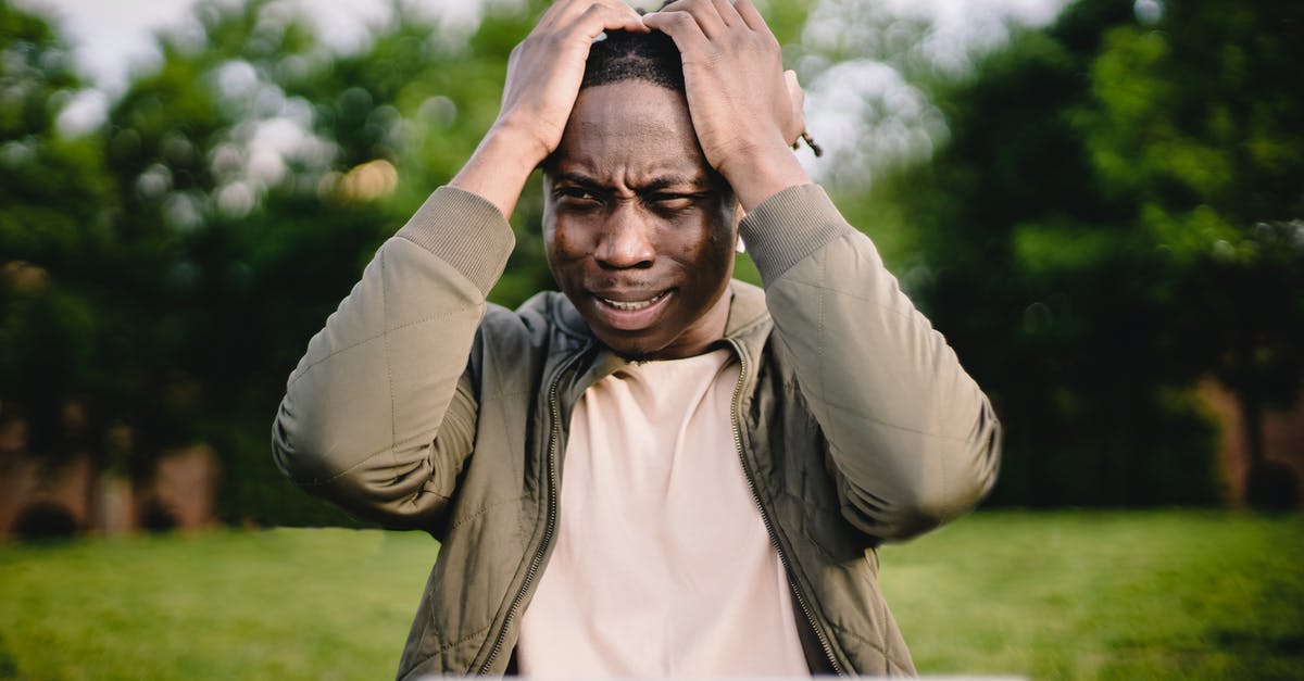 Problems using my black garlic fermenter - Disappointed black man holding head thinking about problem in front of laptop in park