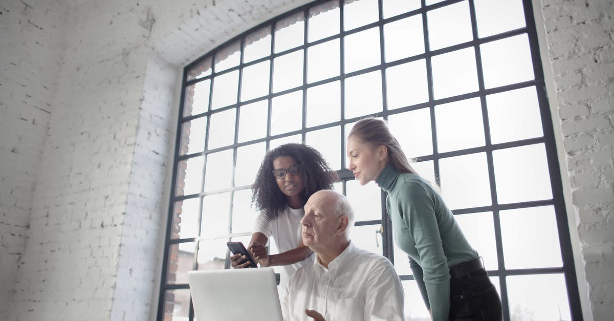 Problems using my black garlic fermenter - Team of businesspeople working on problem together with smartphone and laptop during office job in workplace with industrial interior against big window