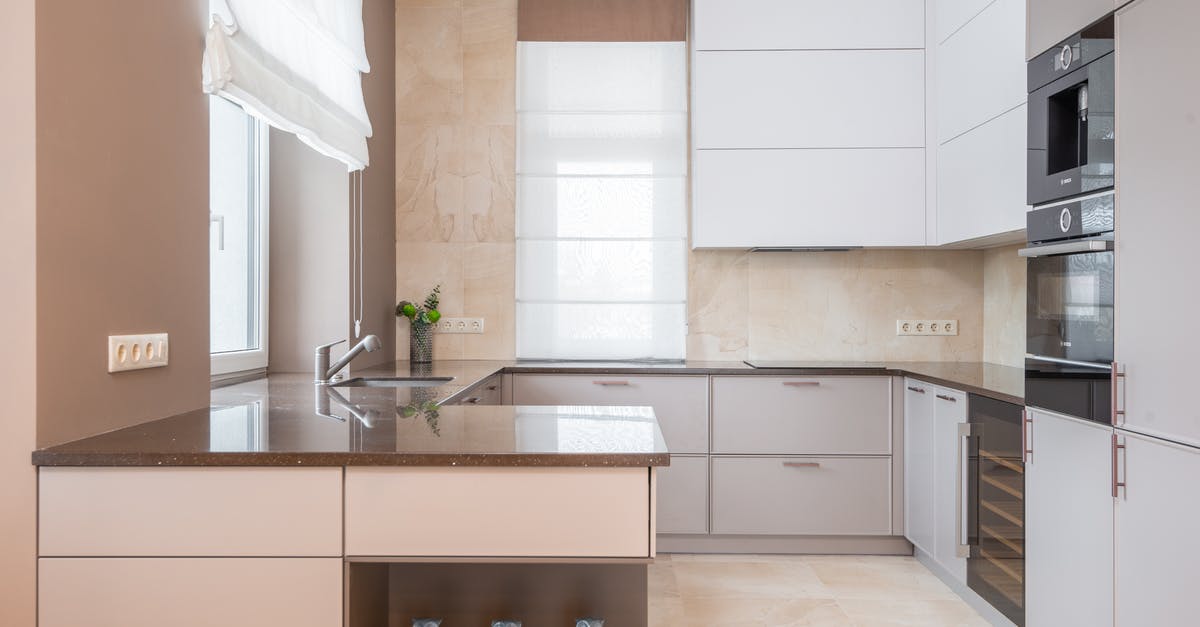 Proper Slow Cooker Usage - Empty contemporary kitchen with beige walls and light floor tile furnished with minimalist cupboards with gray panels equipped with oven and built in appliances