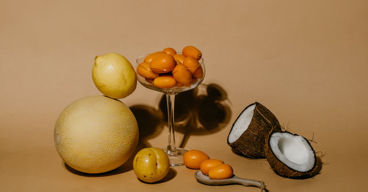 Prosciutto and Cantaloupe - A Bunch of Kumquats in Martini Glass Beside Citrus Fruits and a Sliced Coconut