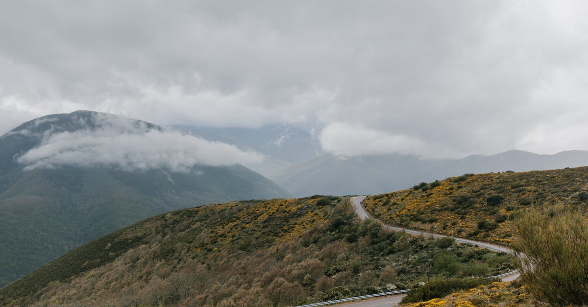 Pumpkin pie filling way too thick - Winding asphalt roadway running through grassy hill covered with grass and shrubs under cloudy sky