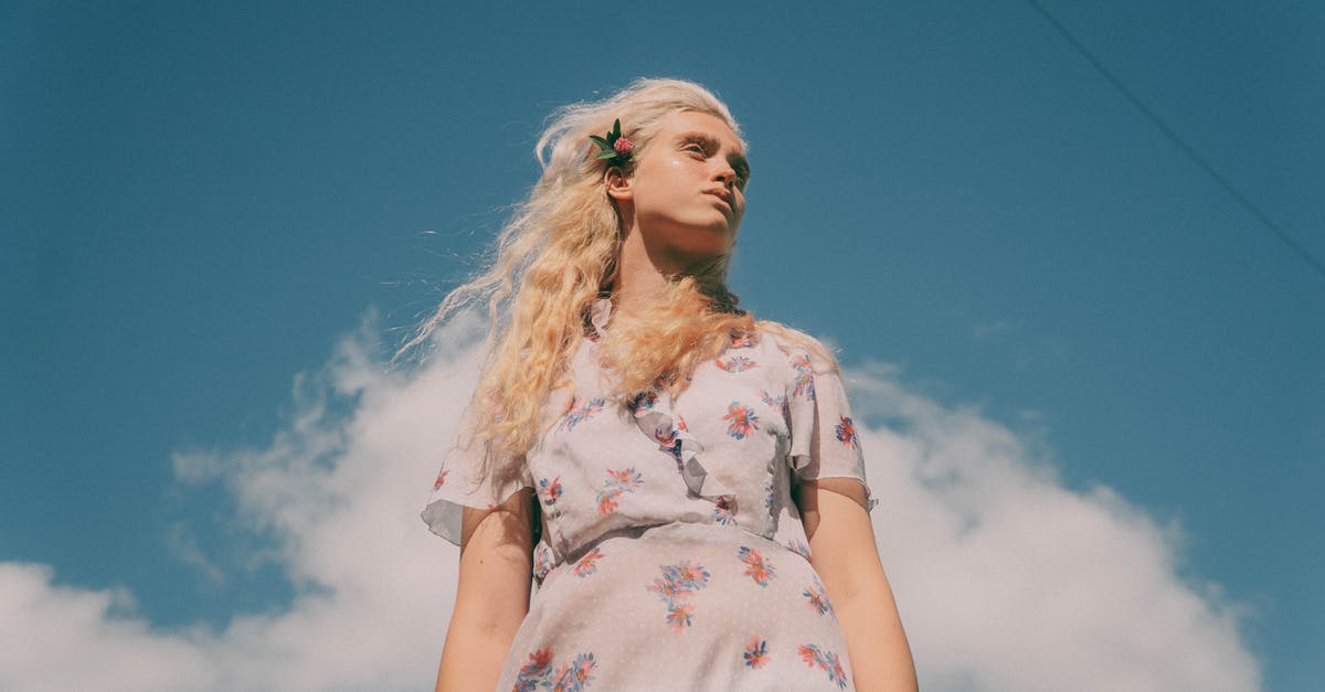 Purging air from a pressure cooker - Low angle of young tender female in dress with floral ornament looking away under cloudy sky