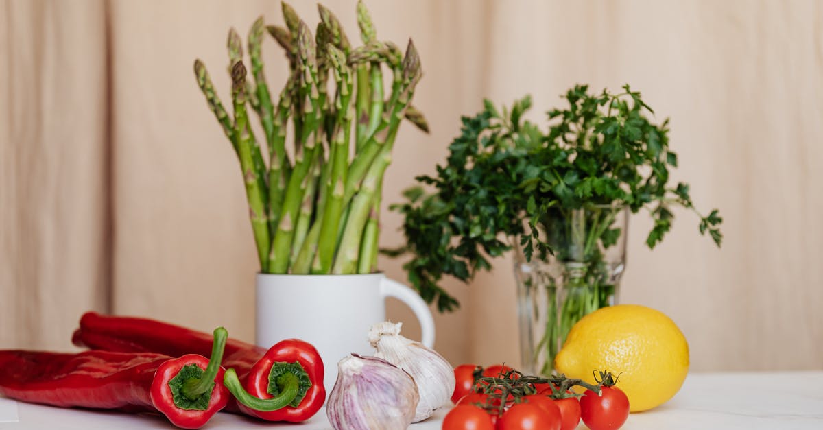 Question about roasting green beans and cherry tomatoes - Composition of red cherry tomatoes and peppers with garlics and yellow lemon near white cup with asparagus and green parsley in glass on table