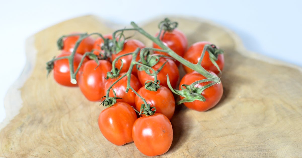 Question about roasting green beans and cherry tomatoes - Red ripe cherry tomatoes on green vine placed on wooden cutting board on white table in light room on blurred background