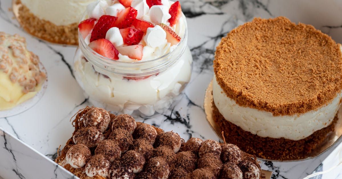 Quick tiramisu with many restrictions - From above of glass jar with creamy parfait with strawberry and round tasty cakes near soft tiramisu served in box