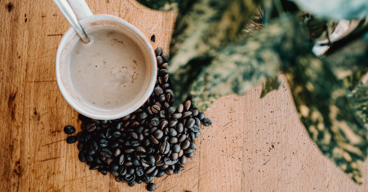 Quickest, and safest way, to bring milk to boil - From above of cup of hot coffee with spoon and brown coffee beans placing on wooden table