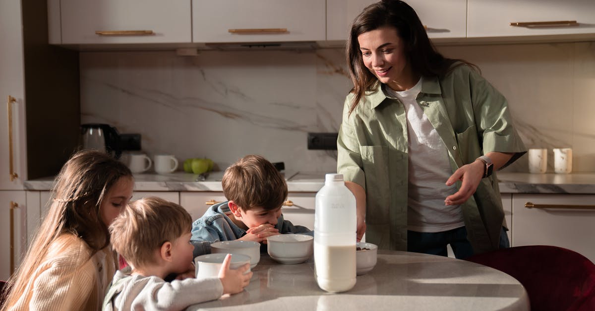 Quickest, and safest way, to bring milk to boil - Woman in Green Button Up Shirt Sitting Beside Child in White Long Sleeve Shirt