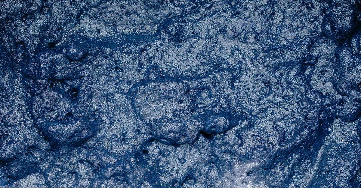 "Lime water" technique -- why use an excess of cal? - From above of surface of foamy indigo colored water during shibori tie dyeing process as abstract background