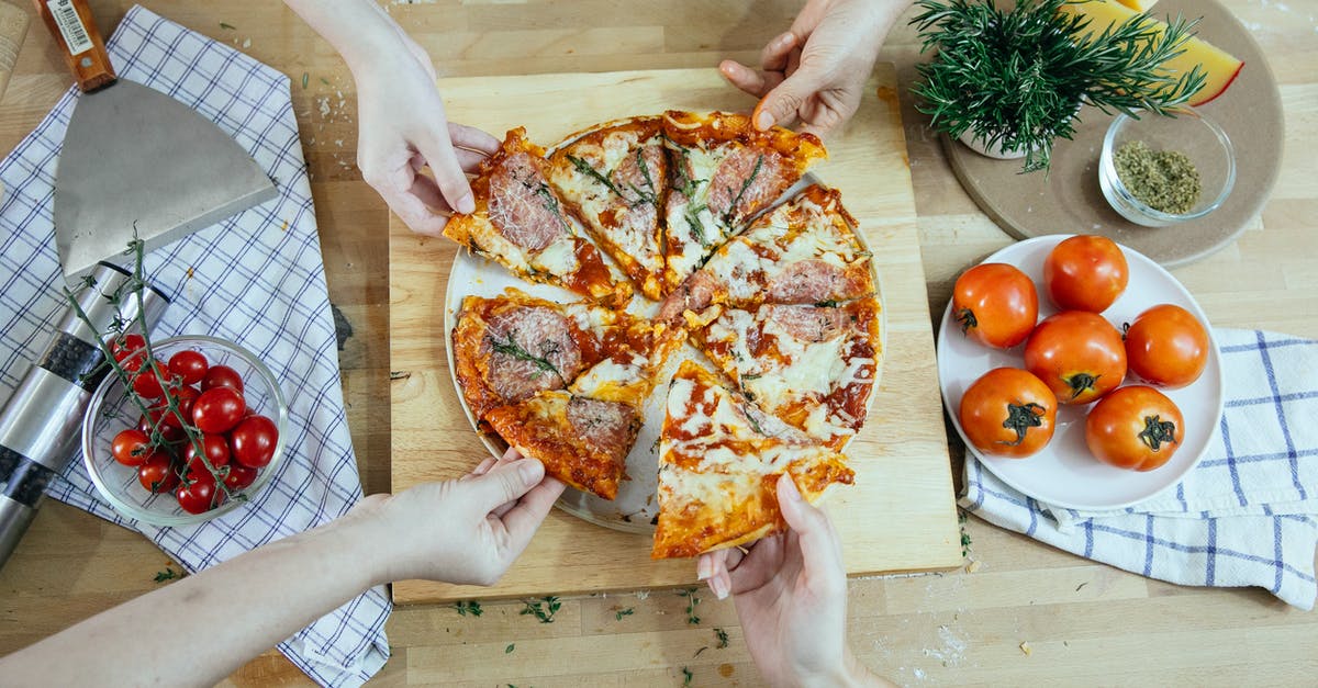 "Parts is parts" in sausages? - From above unrecognizable people taking slices of pizza with salami melted cheese and herbs from plate on kitchen table