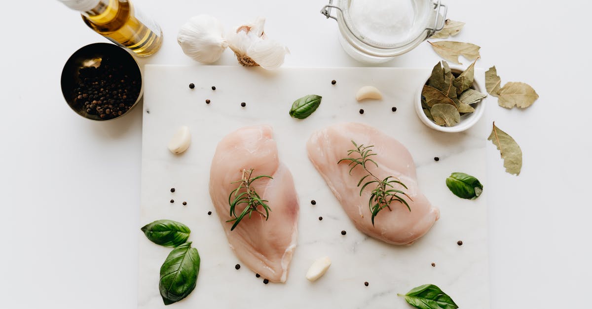 Raw garlic in Sunflower oil - Raw Chicken Breast with Rosemary on the Table