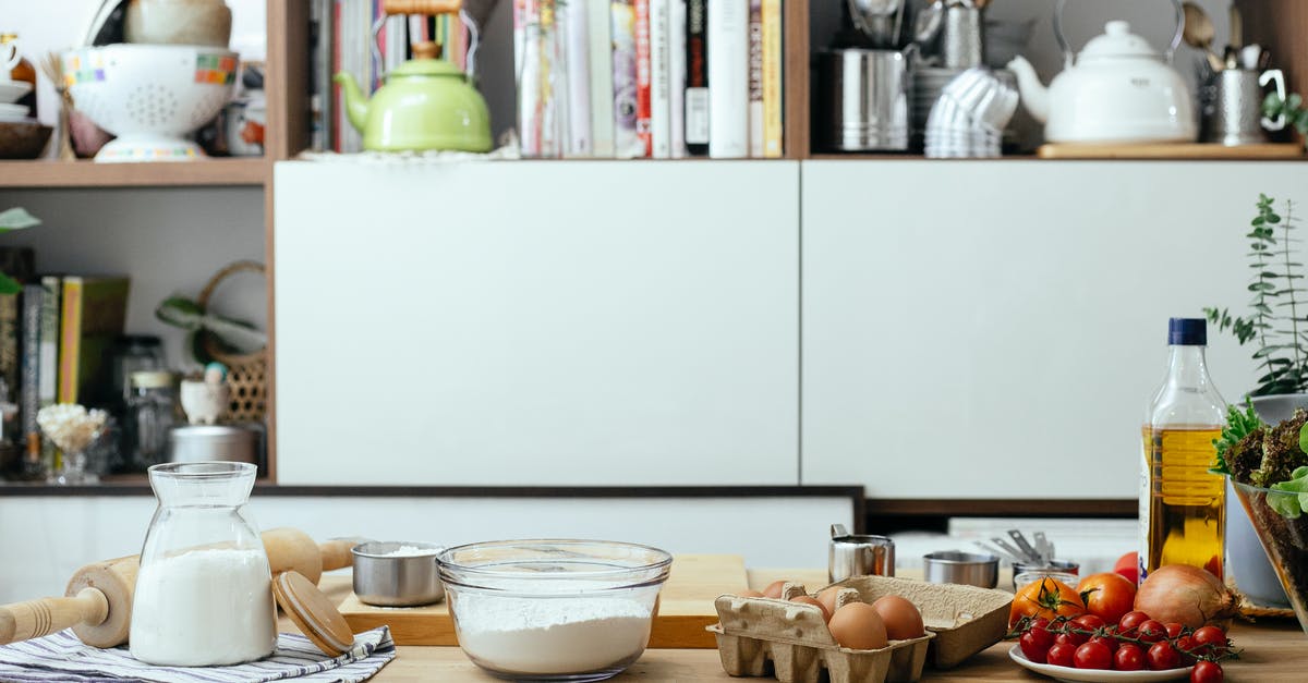 Raw milk curdling in microwave - Bowl of flour and eggs on table with and tomatoes and olive oil in contemporary light kitchen