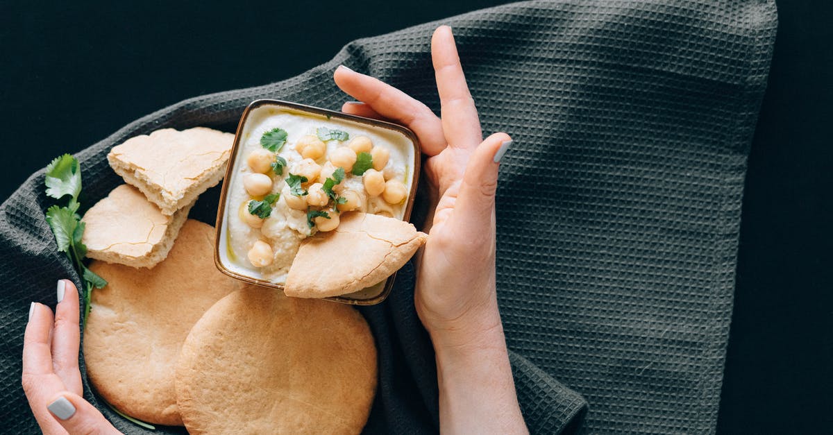 Reason for thickness of pepper\eggplant paste - Photograph of a Person's Hands Near Hummus and Bread