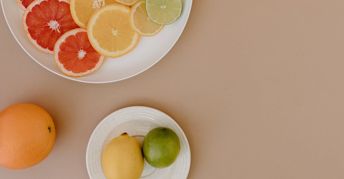Red sweet and sour cabbage...drain or not? - Top view of sliced red grapefruits with oranges near yellow lemons and green limes on plates on beige surface in light place