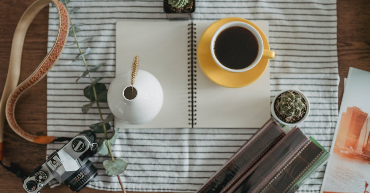 Remove tannins from tea without removing caffeine - From above of cup of coffee and white vase placed near vintage photo camera and potted plants on wooden table in daytime