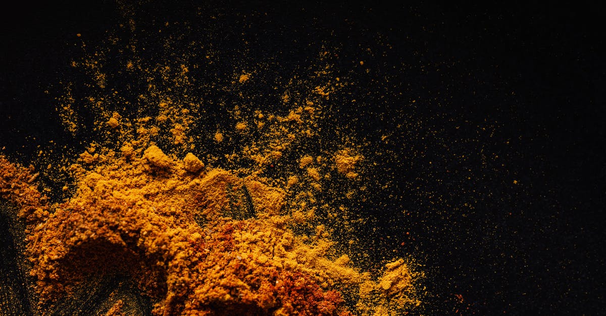 Removing turmeric colour from mortar and pestle - Composition of multicolored ground spices spilled on black background