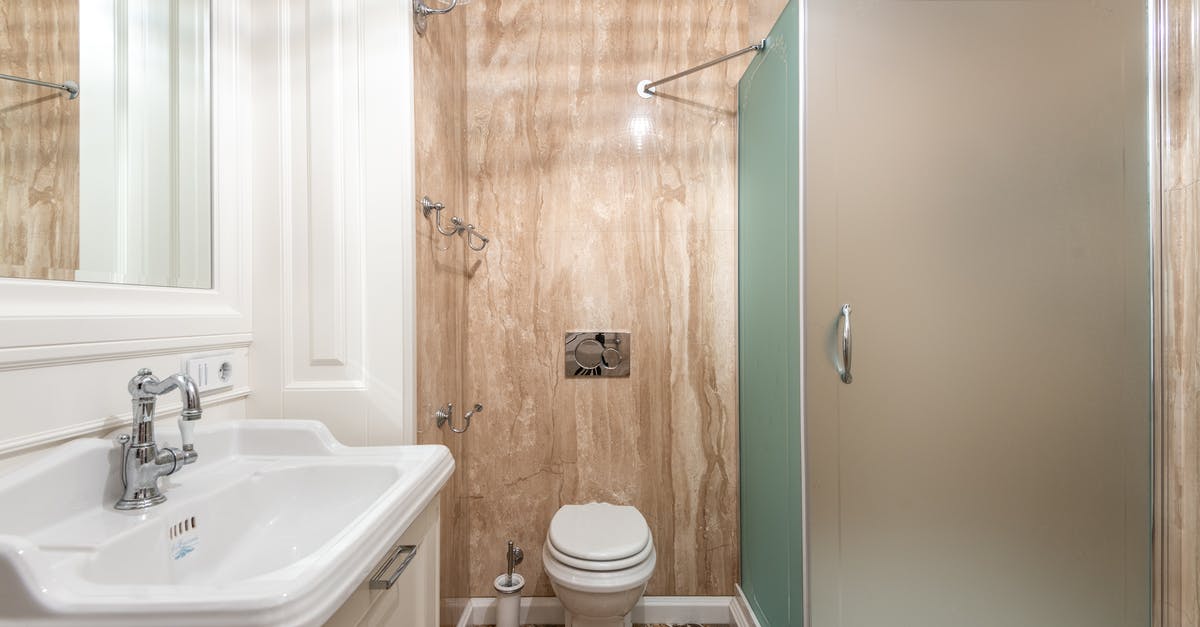 Residue on a new hard-nitriding cast iron skillet - Interior of bathroom with wall mounted toilet and shower cabin at tiled wall near clean sink under bright lighting