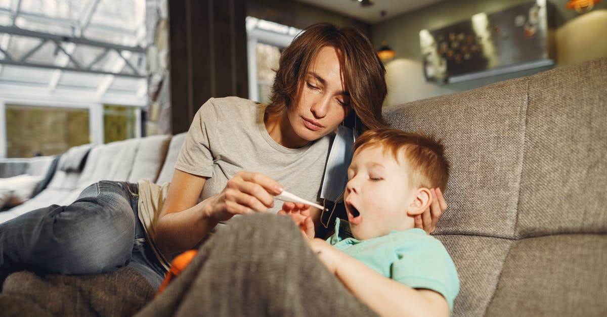 Resting meat - room temperature and bacteria - Mother taking sons temperature while sitting on sofa in apartment