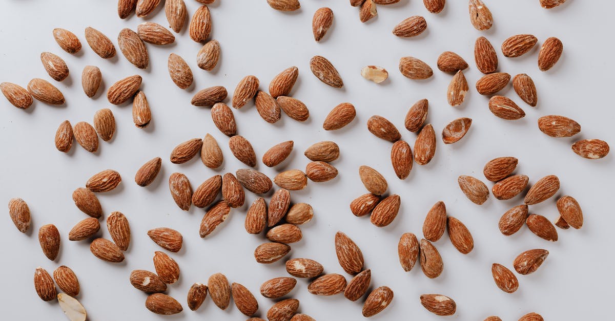 Roast almond for desserts - Top view of pile of delicious almond nuts cluttered on white table illustrating healthy food eating concept