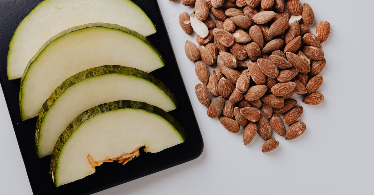 Roast almond for desserts - Pile of almonds and chopped melon on white table