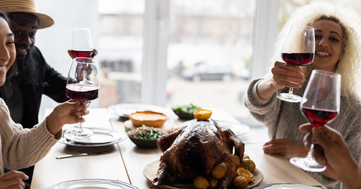 Roast Turkey - rinse or not? [duplicate] - Glad diverse adult friends sitting at table with tasty dishes and toasting with glasses of wine during celebration of Thanksgiving Day