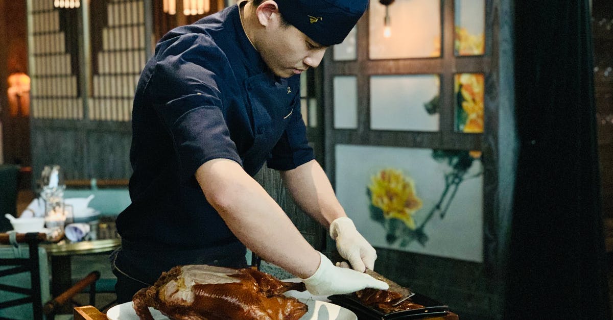 Roasted duck carcass - what is this dish called? - Ethnic male cook cutting roasted duck