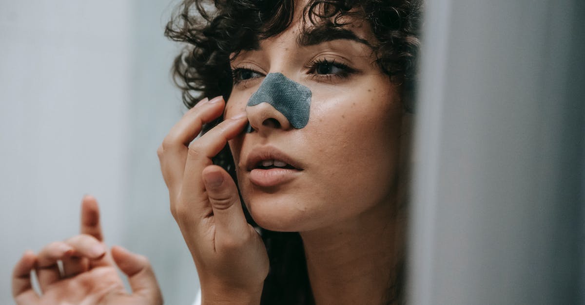 Roasting smaller, thinly skinned peppers - removing peel - Mirror reflection of young female with curly hair putting nose strip mask on face in bathroom