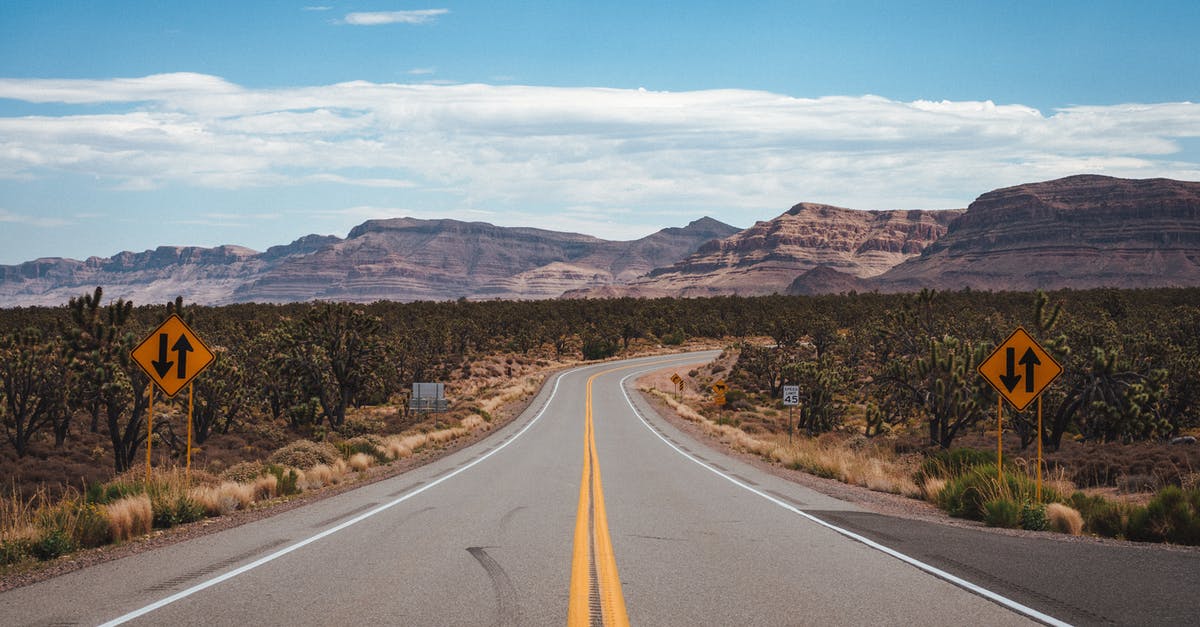 Rocky road seized up? - Empty asphalt road going through cactus fields towards rocky mountains against cloudy blue sky in United States of America