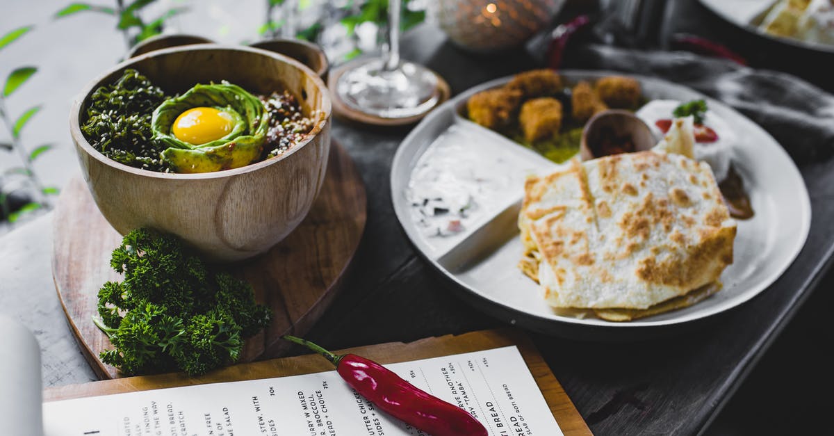 Roti Canai cooking tips? - High angle of plate with roti bread and different Asian snacks placed on table with bowl of exotic food served with eggplant and avocado