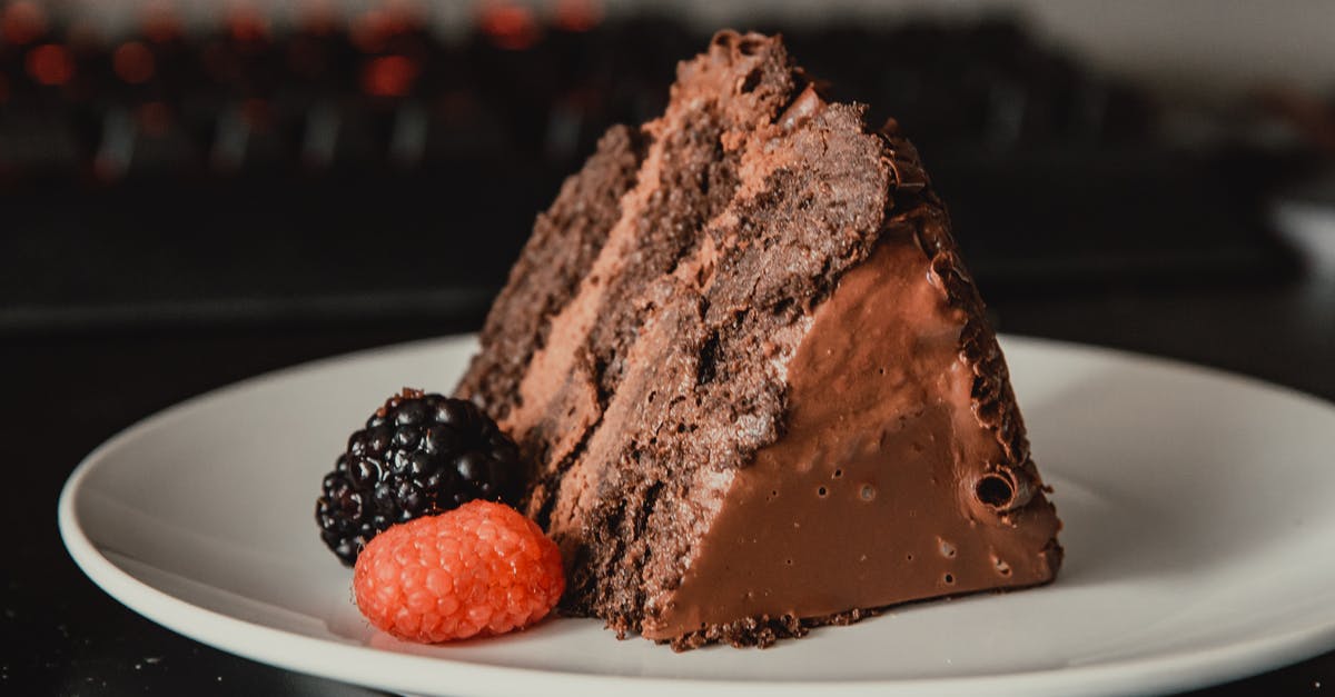 Russian Pie Recipe breaks into little pieces? - Appetizing sweet dark chocolate cake served on white plate and decorated with ripe black and red blackberries