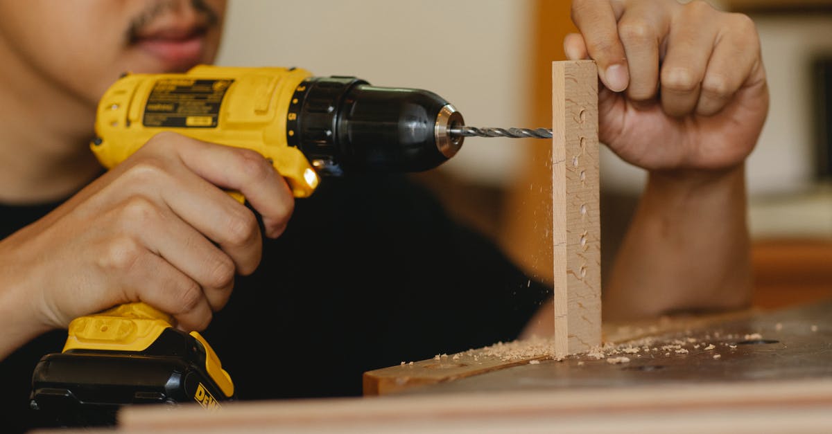 Safe kitchen-ready materials to drill holes in for tofu press? - Crop anonymous male drilling holes in wooden panel while working on table in workshop