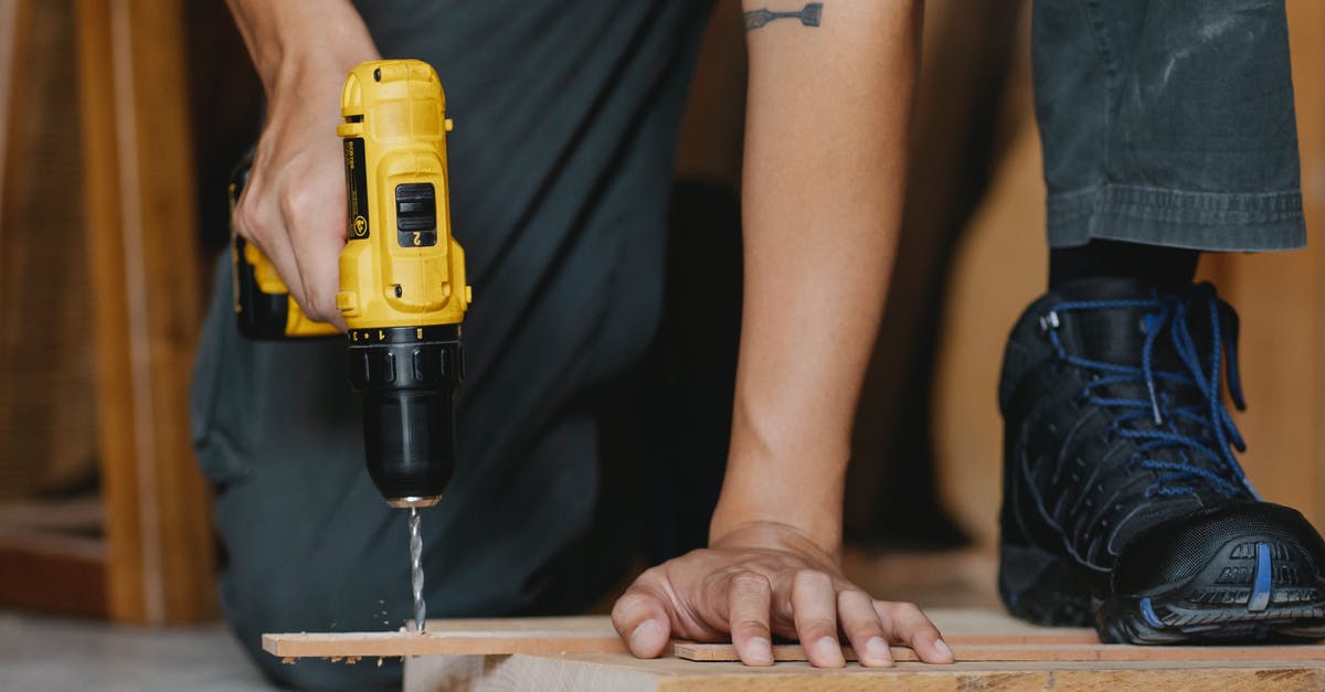 Safe kitchen-ready materials to drill holes in for tofu press? - Crop anonymous male drilling and pressing timber detail with foot in boot in workshop