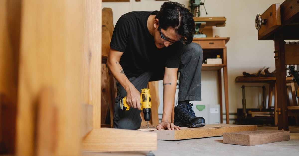 Safety glasses in the kitchen: why are these not common place? - Pensive male drilling wooden surface of plank in workshop with equipment for carpentry