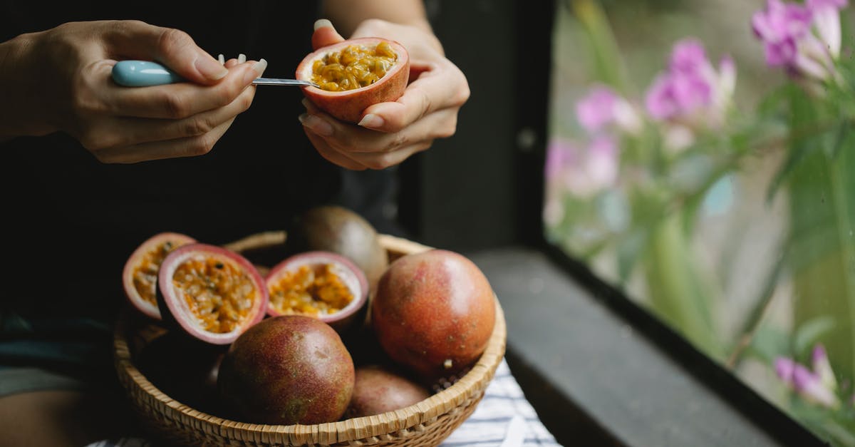 Salad ingredients: how to pick them at the market? - Unrecognizable woman picking up juicy pulp of passion fruit while cooking healthy lunch