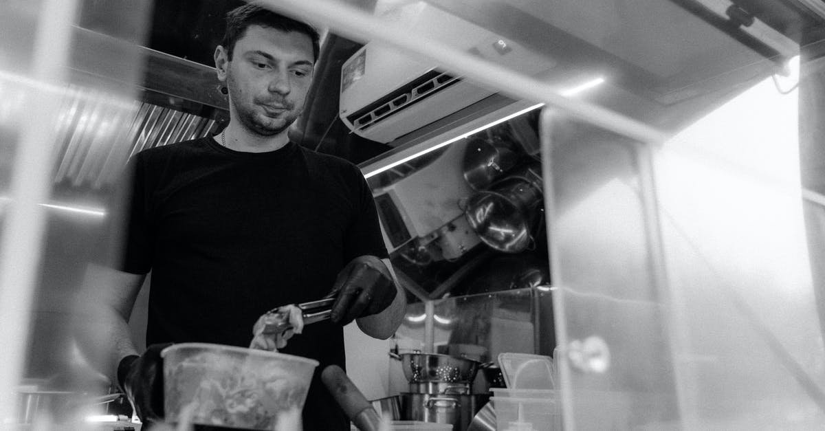 Sanitising Black chef "whites" - A Grayscale of a Man Wearing a Black Shirt Working in a Kitchen