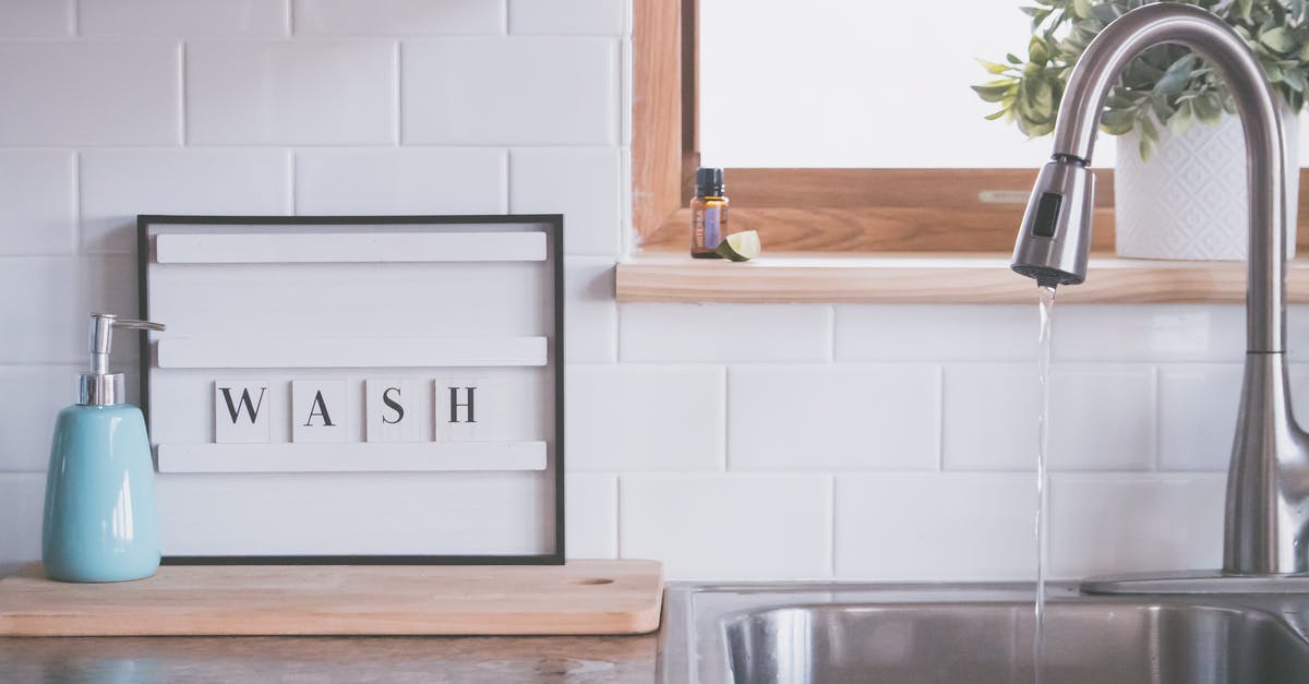 Sanitization, disinfection, sterilization of Dishwasher? - Board with word WASH placed near soap dispenser on counter in bathroom with water streaming from open faucet