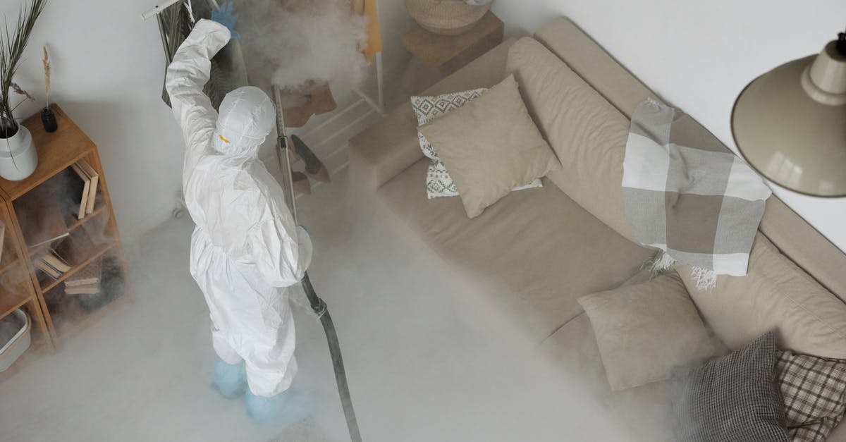 Sanitizing a meat rack - A Man Wearing White Protective Clothing Fumigating Clothes