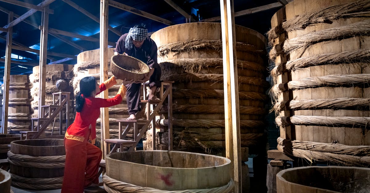 Sauce thickener for large batch - Woman helping male colleague standing on ladder while working in fish sauce factory together