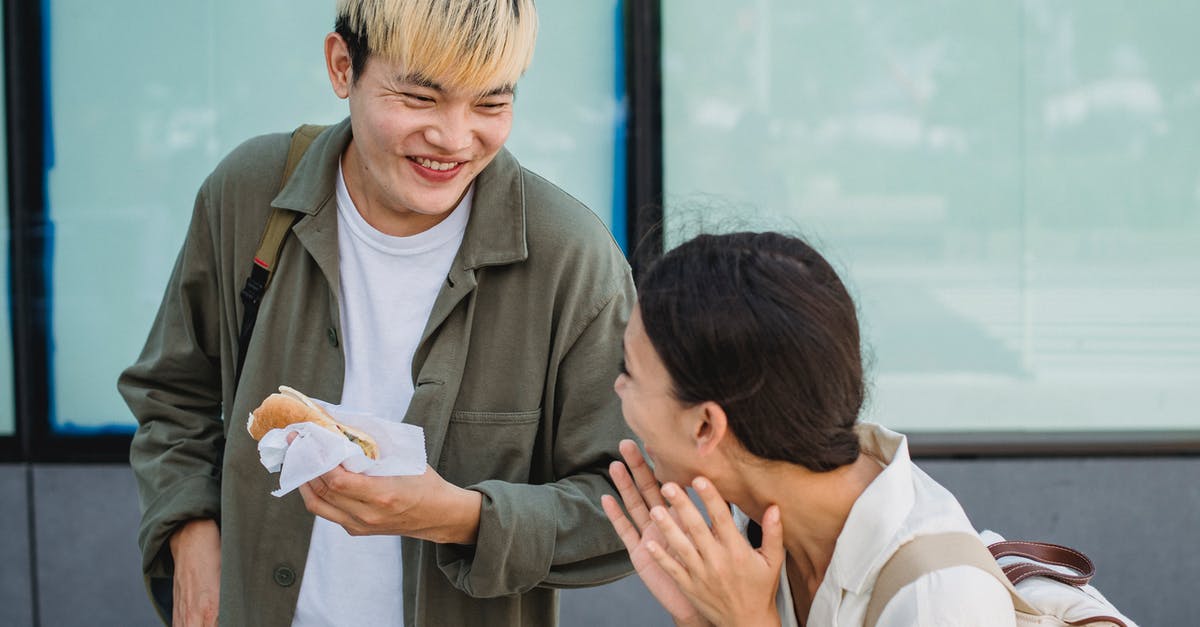 Sausage exploded and looks foamy - Joyful Asian couple enjoying hot dog on street