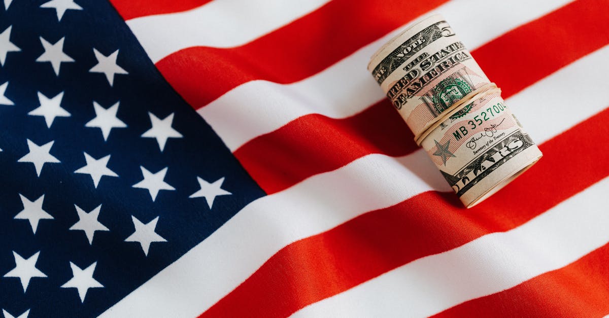 Saving spoiling mushrooms? - From above of United States currency folded in roll placed on USA flag illustrating concept of business profit and wealth