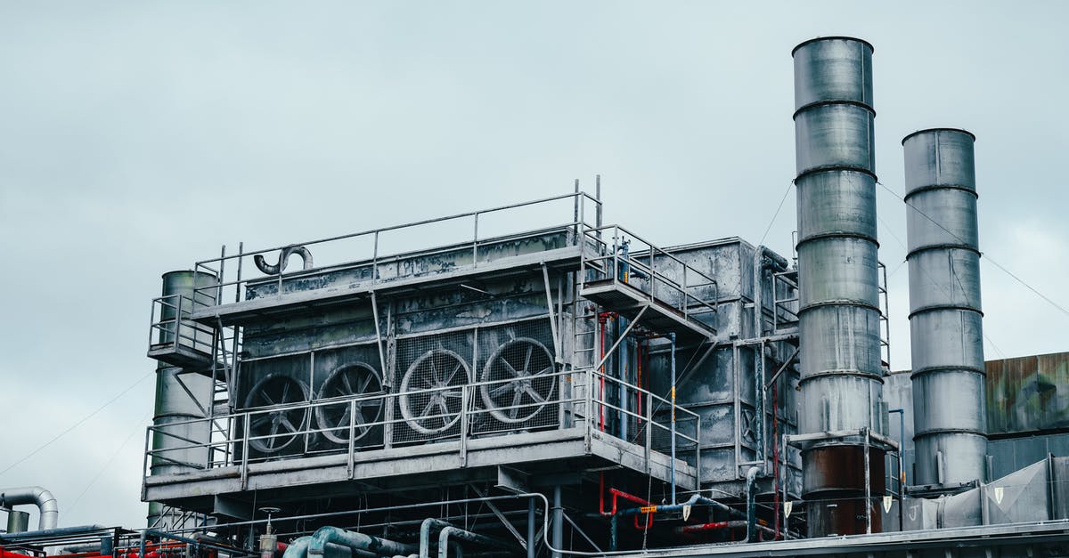 Scale build up on outside of cast iron skillet - Exterior view of large industrial construction with metal tubes located on factory in daytime on cloudy weather