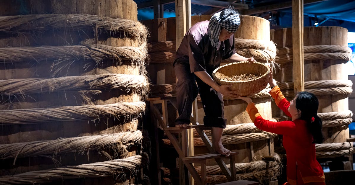 Seasoning a wok, have I burned on the factory oil? - Serious ethnic male worker standing on ladder near barrels with fish sauce while working with colleague