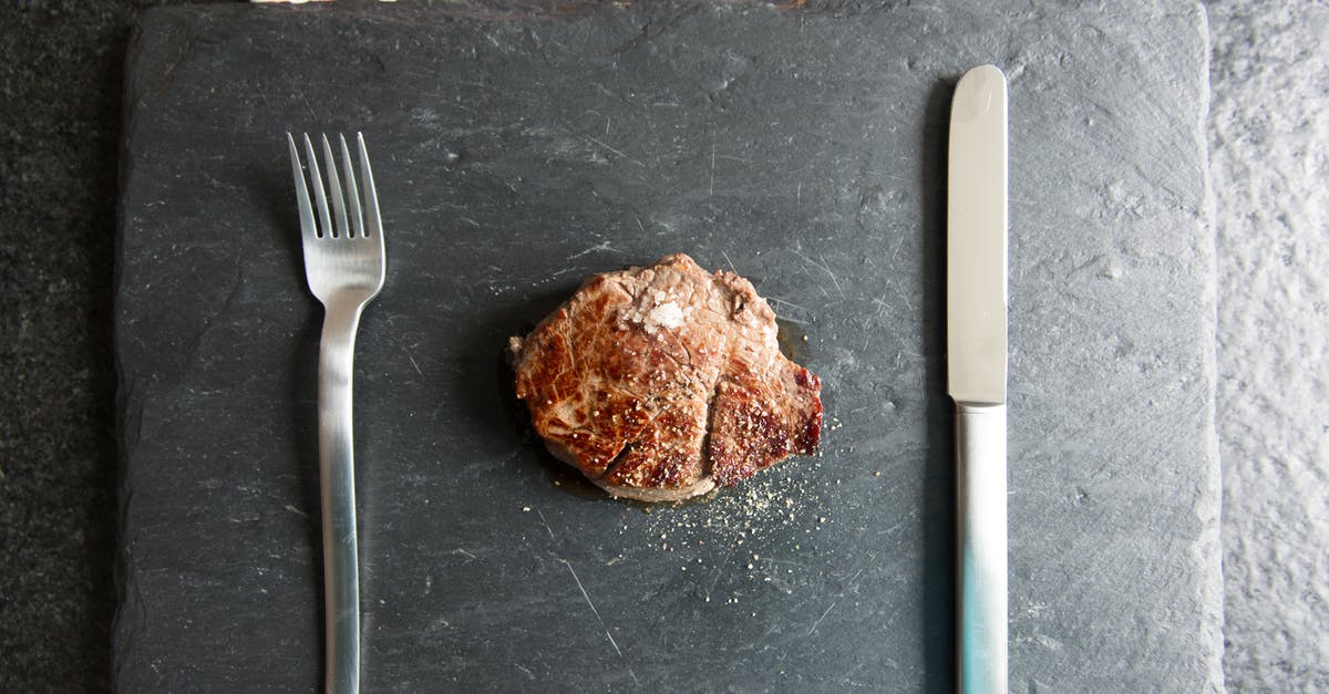 Seasoning steak with broiler salt - White Handled Fork Beside Brown Bread