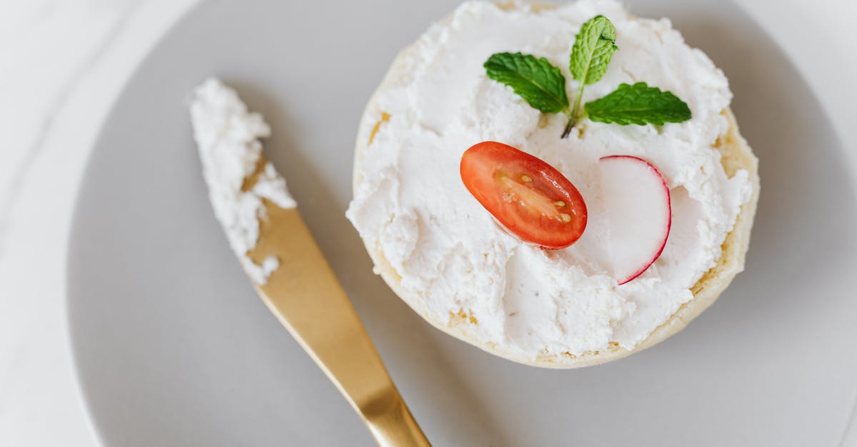 Seeking a creamy/melty Swiss Cheese commonly available in the US - From above of delicious cottage cheese spread on bun decorated with vegetables and mint on round platter with golden knife placed on marble table