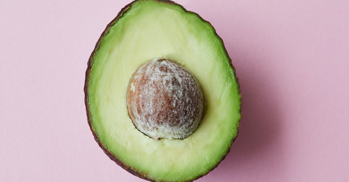 semi-freezing ripe avocado for easier handling - From above of half of fresh raw ripe avocado with seed on purple background