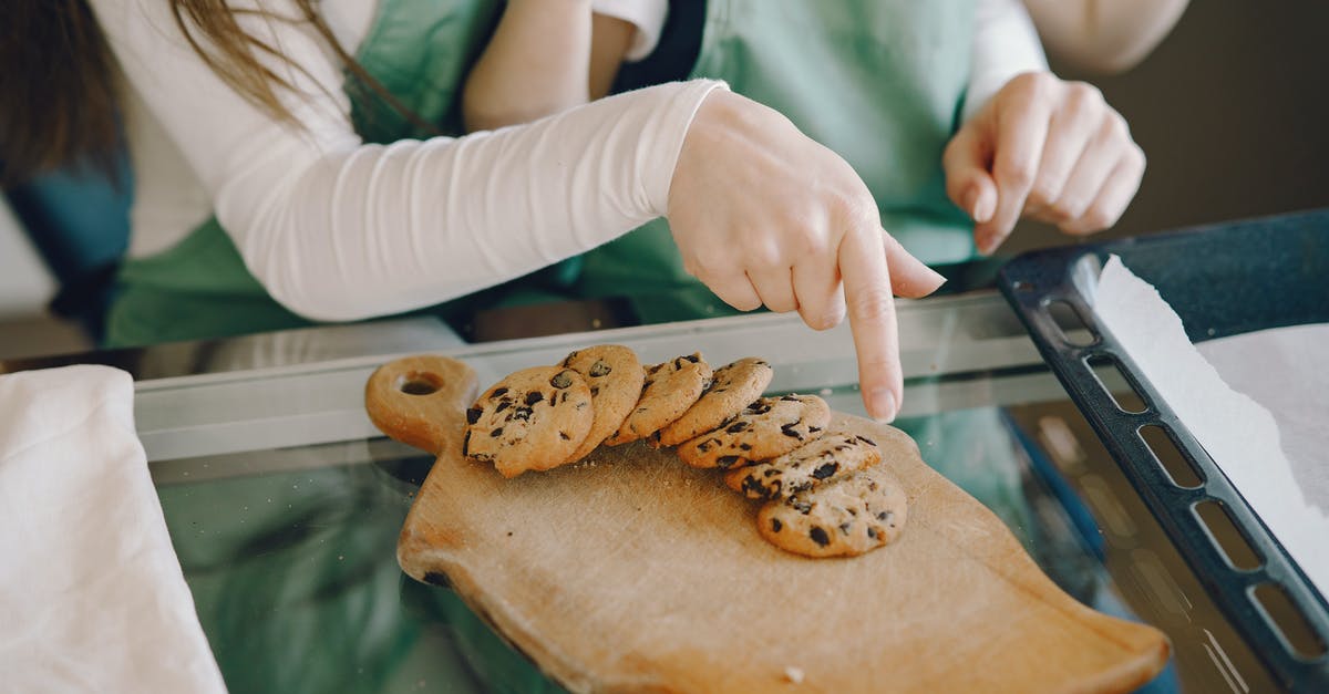 Separating chocolate-coated cookies stuck together - Crop woman and child with homemade cookies at home