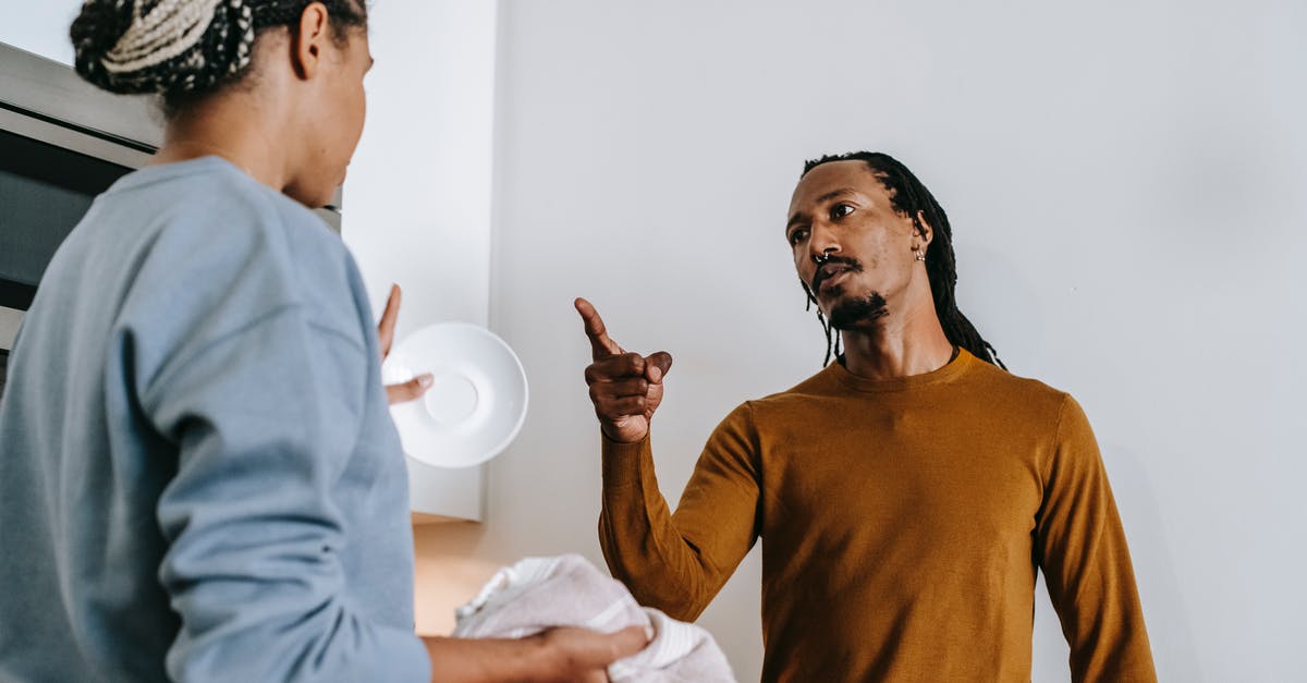 Settling Up the Dispute over Poached Egg's Definition - Annoyed African American male with finger up menacing to anonymous female partner while arguing in kitchen and looking at each other